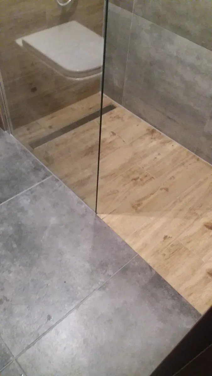 Styk płytek drewnopodobnych i grafitowych przy ściance prysznica walk-in