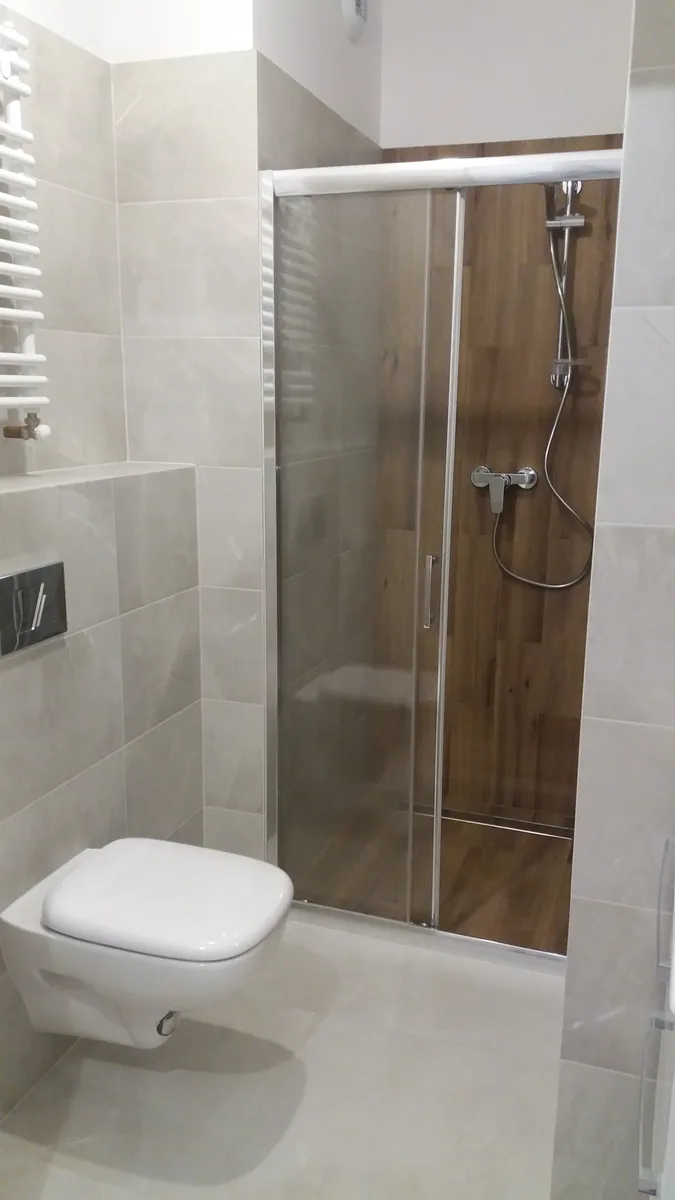 Łazienka z wielkoformatowym gresem szaro-beżowym, przeszkloną kabiną prysznicową z drewnopodobną ścianą i podwieszanym WC — Sołtysowice, Wrocław