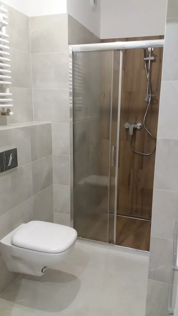 Łazienka z wielkoformatowym gresem szaro-beżowym, przeszkloną kabiną prysznicową z drewnopodobną ścianą i podwieszanym WC — Sołtysowice, Wrocław