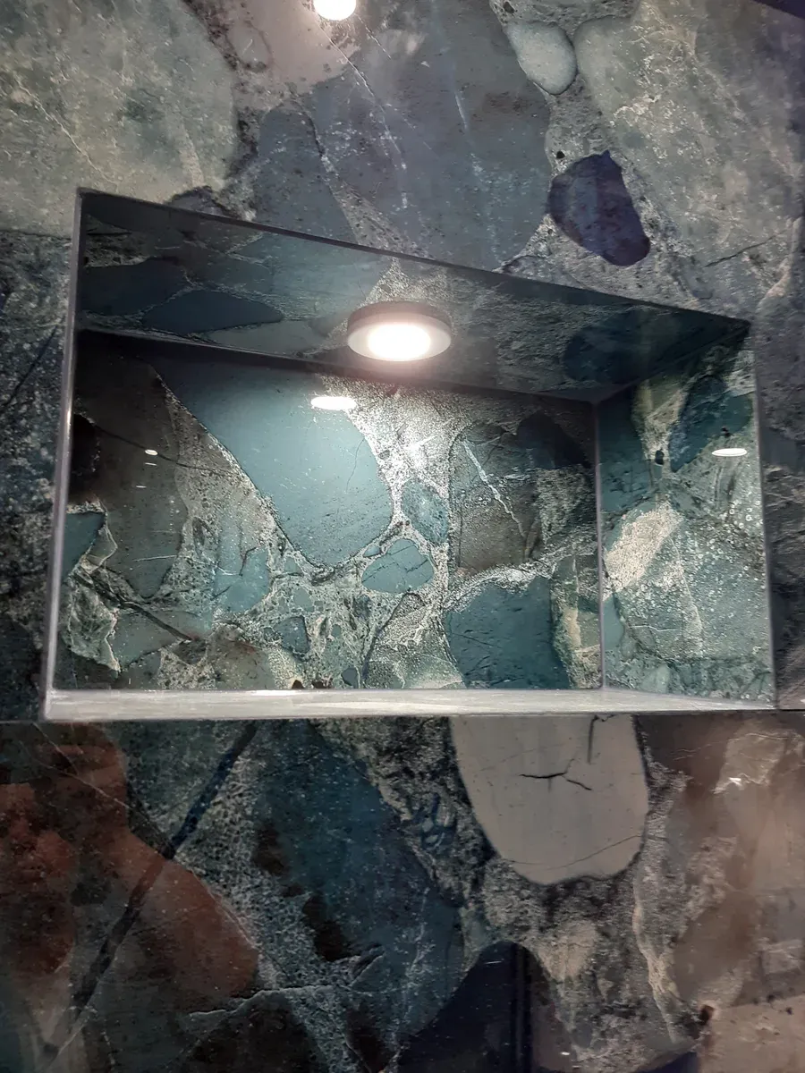 Detale prysznica — armatura chromowana na tle zielonego marmuru