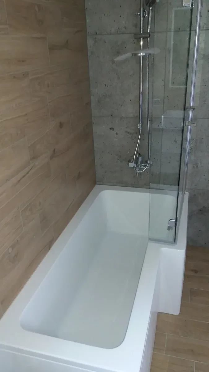 Prysznic walk-in z siedziskiem z białego konglomeratu i ścianą betonową