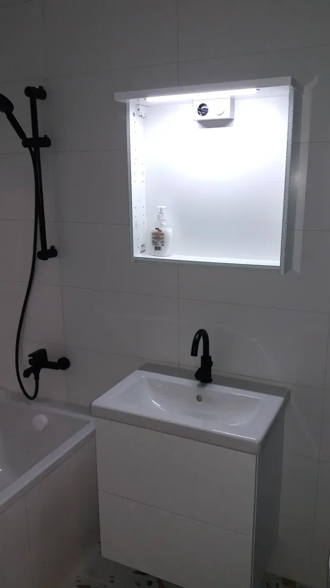 Biała łazienka z podłogą lastryko (terrazzo), czarną armaturą, wanną i podświetlaną wnęką z półką — Ołbin, Wrocław